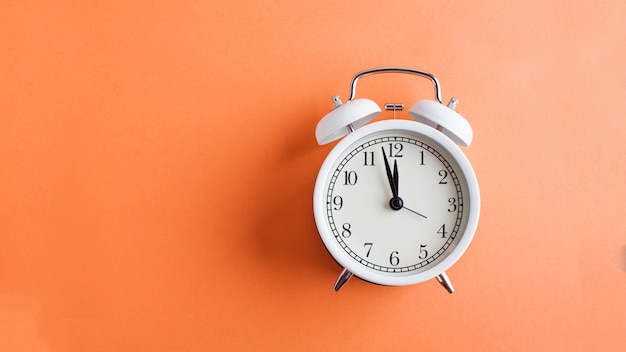 Banner white alarm clock on a colored orange background. Minimalism. Art concept of time, start. Copy space.