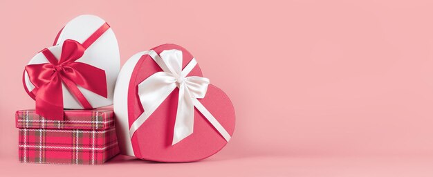 写真 ピンクの背景のバレンタインデーにハートの形をしたギフトボックスを掲げたバナー