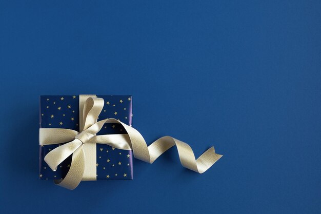 Banner with blue gift box with gold ribbon on a blue background top view copyspace