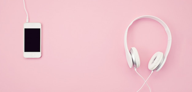 Photo banner with the cell phone and headphones over the pink background. music, entertainement, online playlists