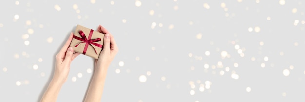 Banner with female hands hold gift box with red bow