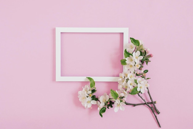 Banner with flower and empty white photo frame on pink background with copy space space