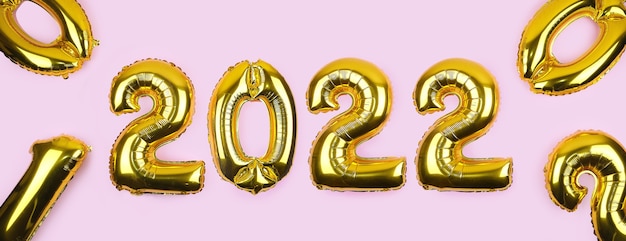 Banner with golden foil balloons on pink background numbers gold balloons on pink wall new years