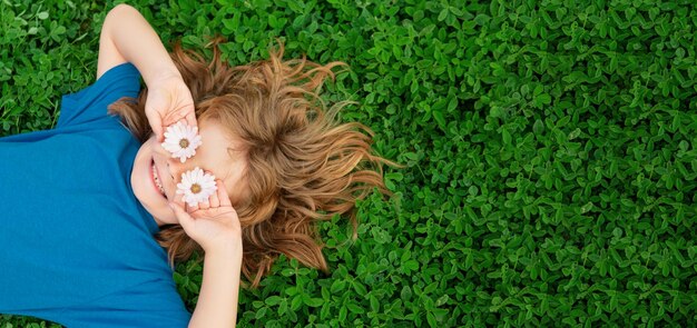 Banner with spring child face happy child lying on green grass outdoors in spring park kids on green