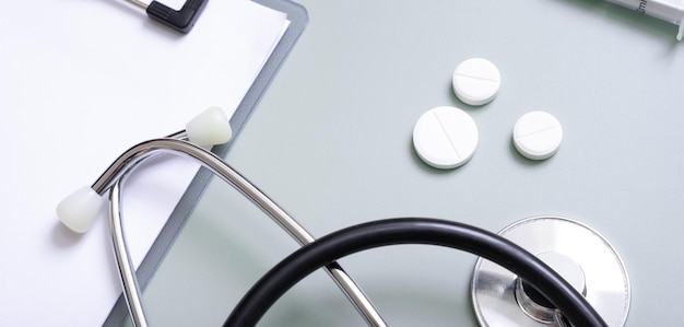 Banner with stethoscope pills and tablet at doctor's workplace on colored background top view