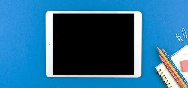 Banner with tablet mockup screen, education concept and school workspace flat lay blue desktop background, top view photo