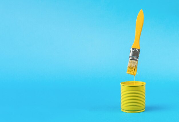 Photo a banner with a yellow brush with dripping paint over a jar on a blue background a place for your text trending colors minimal concept of interior selection