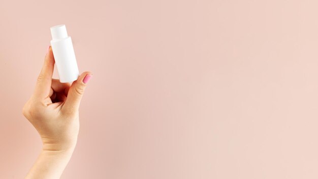 Banner a woman39s hand holds a white tube with a cosmetic product on a pink background Beauty product concept Sample