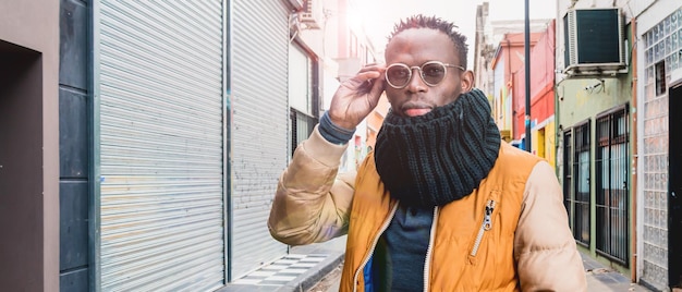 Banner of young african man outdoors looking at the camera touching his glasses with one hand