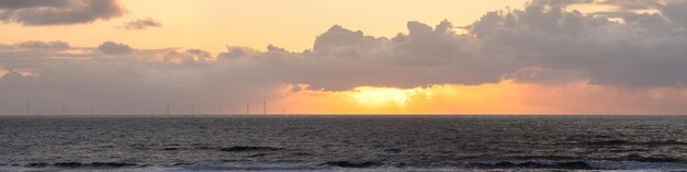 Foto banner zonsondergang over de zee windmolens langs de horizon