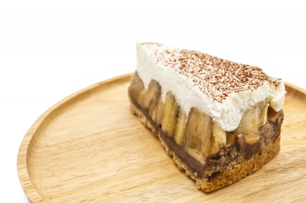 Banoffee Pie, whipped cream and banana on the wooden plate isolate white background