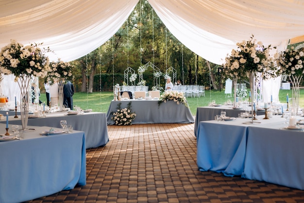 Banquet hall in a tent with blue tablecloths and decorations