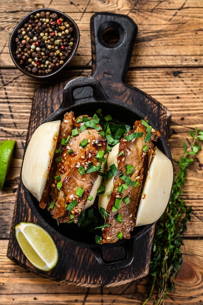 Bao bun, gestoomde sandwich met varkensvlees. Houten achtergrond. Bovenaanzicht.