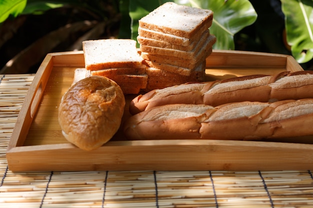 Бакет и хлеб из зерновых культур помещают в деревянный поднос с естественным освещением на открытом воздухе.
