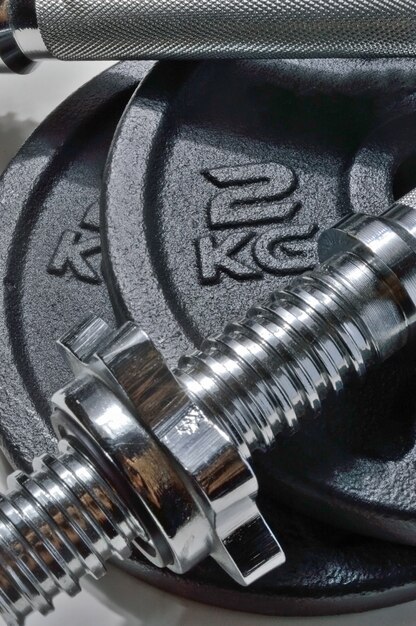 Bar and black discs of a collapsible dumbbell with weight designation. close-up.
