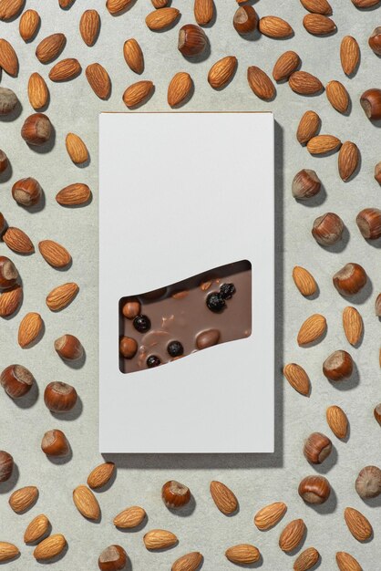 A bar of chocolate in a package on a gray background with nuts