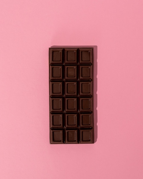 Bar of dark chocolate on a pink background