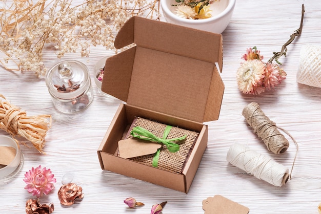 Bar of homemade soap wrapped in hemp fabric on wood background