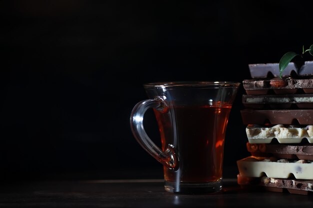 Una tavoletta di cioccolato al latte. cioccolato al latte fatto in casa con mandorle e fragole secche. pezzi di cioccolato al latte. tavoletta di cioccolato al latte senza etichetta. set di cioccolato con tè.