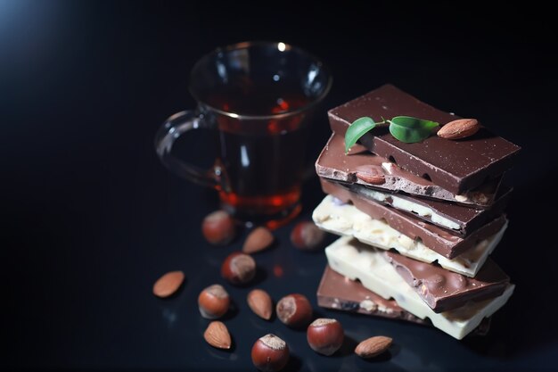 A bar of milk chocolate. Homemade milk chocolate with almonds and dried strawberries. Pieces of milk chocolate. Unlabeled milk chocolate bar.Set of chocolate with tea.