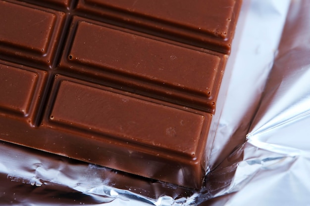 Bar milk chocolate lies on foil