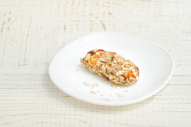 Bar of muesli on a white saucer.  White wooden table