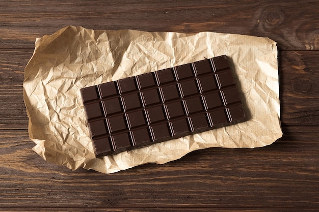 写真 木製の茶色の背景の上面図に黒い苦いチョコレートのバー