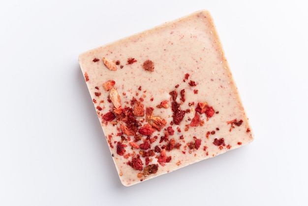 A bar of white chocolate with freeze-dried strawberries on a white background