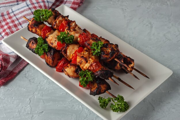 Barbecue of chicken on skewers with vegetables on a gray background