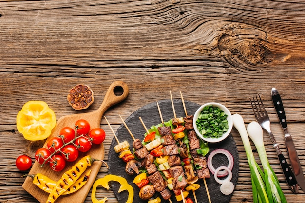 Barbecue of chicken on skewers with vegetables on wooden background