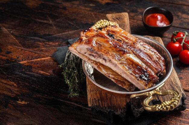 Barbecue chopped pork spare ribs in a skillet Wooden background Top view Copy space