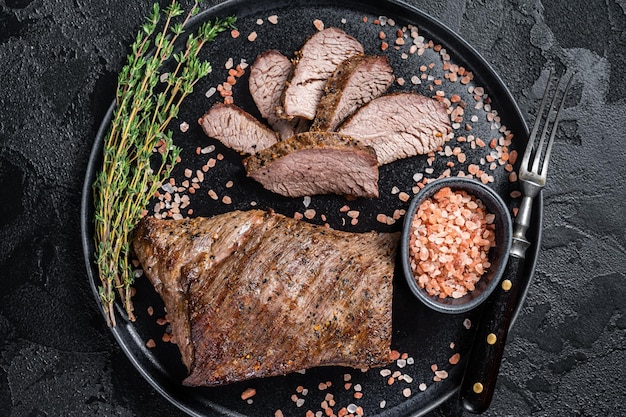 Barbecue droge leeftijd Wagyu Tri Tip biefstuk op een bord met roze zout Zwarte achtergrond Bovenaanzicht