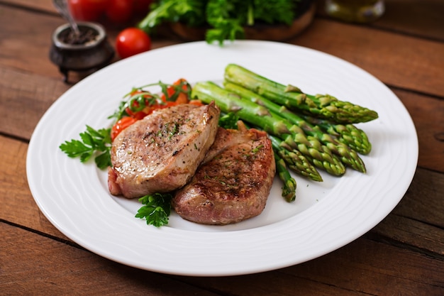 Foto barbecue gegrild vleesbiefstuk vlees met asperges en tomaten.