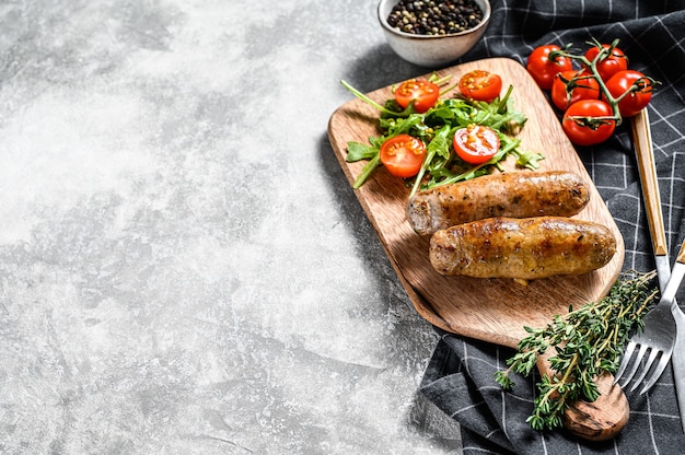 Barbecue gegrilde varkensworst met een bijgerecht van tomatensalade en rucola