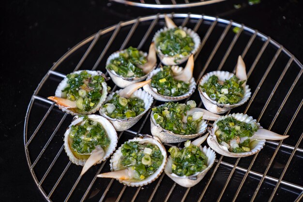 Barbecue grill cooking seafood grilling seashells with green onion Vietnam close up