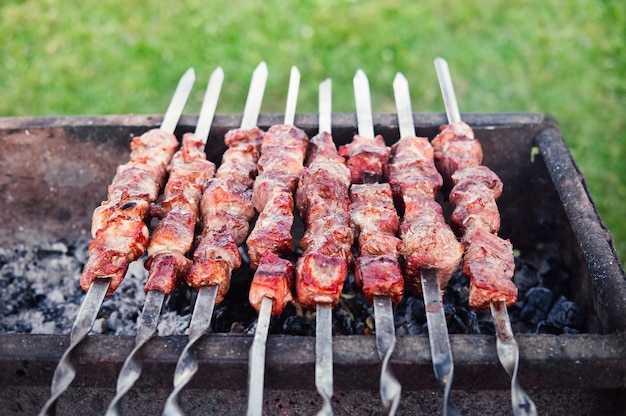 Barbecue alla griglia. kebab su spiedini che cucinano all'aperto. cuocere gli shashlik su spiedini all'aria aperta.