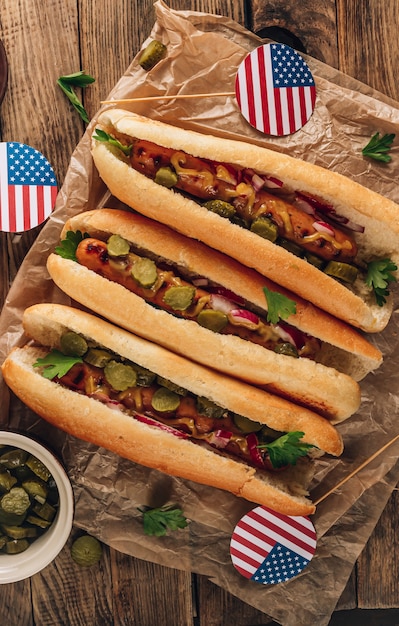 Barbecue grilled hot dog with pickled cucumber, red onion and mustard on rustic wooden background. Top view