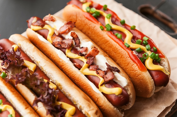 Photo barbecue grilled hot dogs with  yellow american mustard, on a dark wooden background