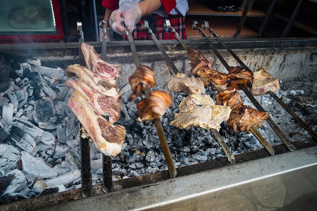 バーベキューでは、多くの肉が串に刺され、シェフがシシカバブをひっくり返します。男性の手が、キャンプで串に刺しておいしい豚肉を揚げます。