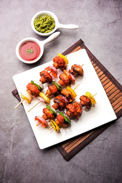 Barbecue of tandoori Mushroom Tikka, geserveerd in een bord met groene chutney en ketchup. selectieve focus