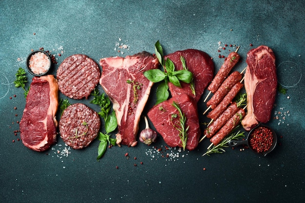 Photo barbecue party tbone steak ribeye steak kebab and burger patty on a black stone background top view