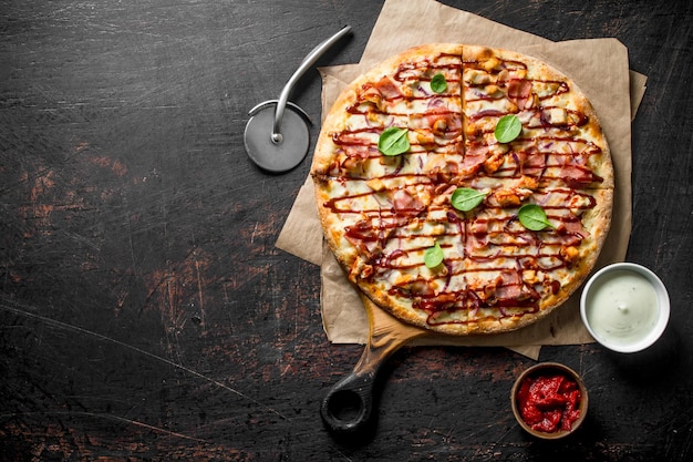 Photo barbecue pizza with cheese and tomato sauces in bowls