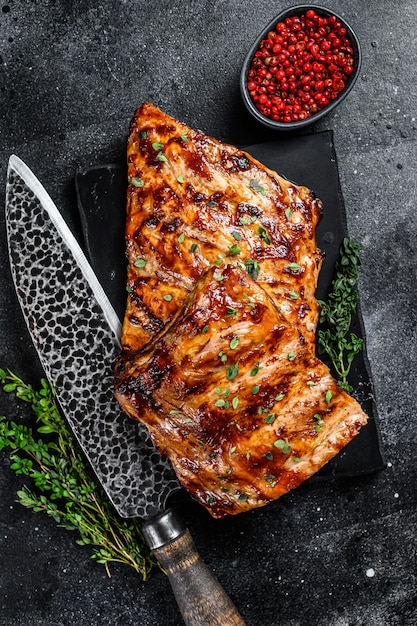 Barbecue pork rack spare ribs on a marble board. Black background. Top view.