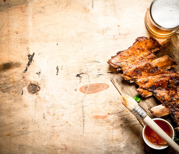 Barbecue pork ribs with tomato sauce and beer on wooden background