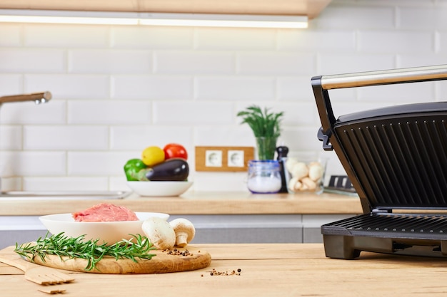 Barbecue preparing in the kitchen interior Electric grill barbecue and meat on kitchen table