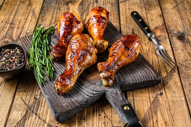 Barbecue roasted chicken drumsticks on a wooden cutting board. wooden background. top view.