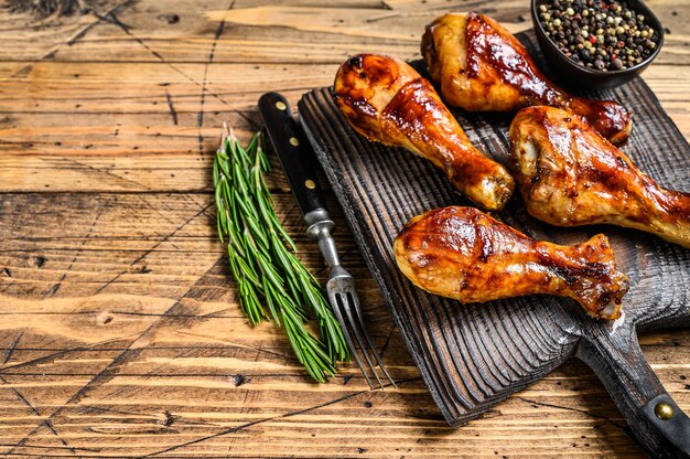 Barbecue roasted chicken drumsticks on a wooden cutting board. 