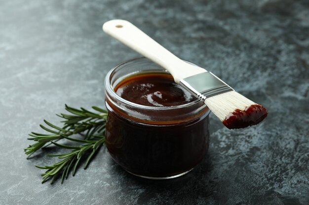 Photo barbecue sauce, rosemary and brush on black smoky