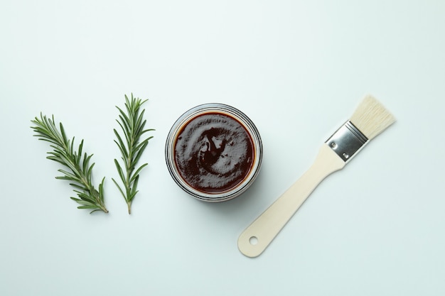 Barbecue sauce, rosemary and brush on white background