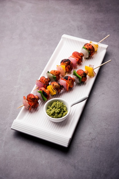 Barbecue or tandoori Mushroom Tikka, served in a plate with green chutney and ketchup. selective focus